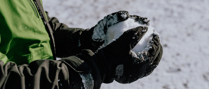 child with gloves on rolling a snowball