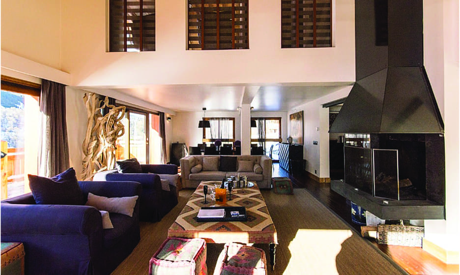 Chalet Impala lounge with blue sofas, open fireplace and high ceiling