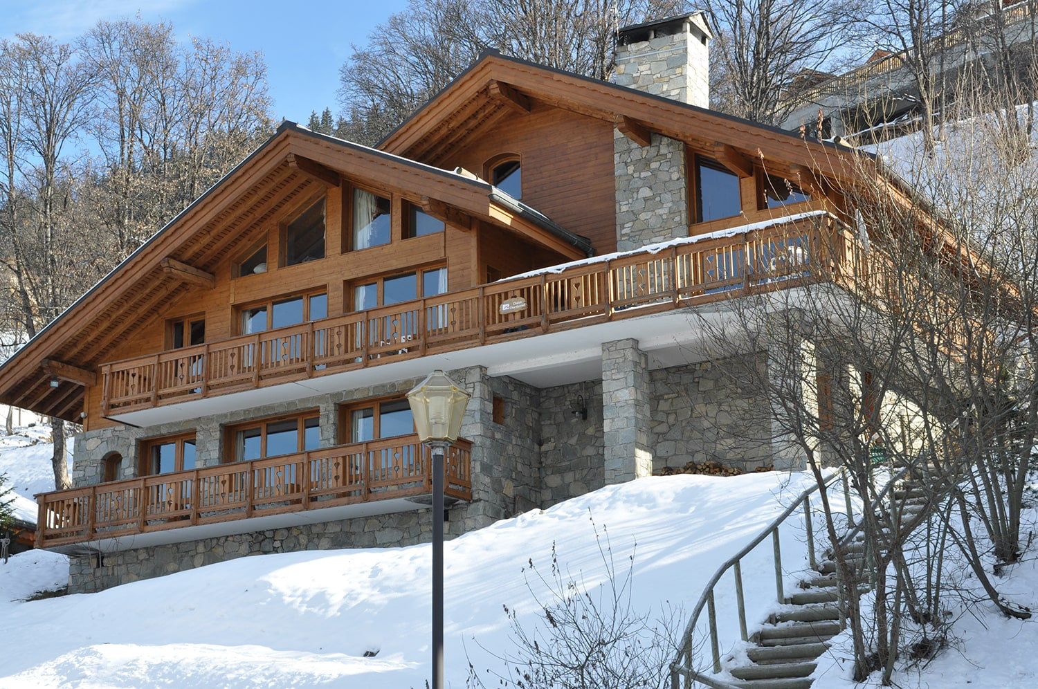 Chalet Le Chardon timber and stone exterior with wooden balconies in snow